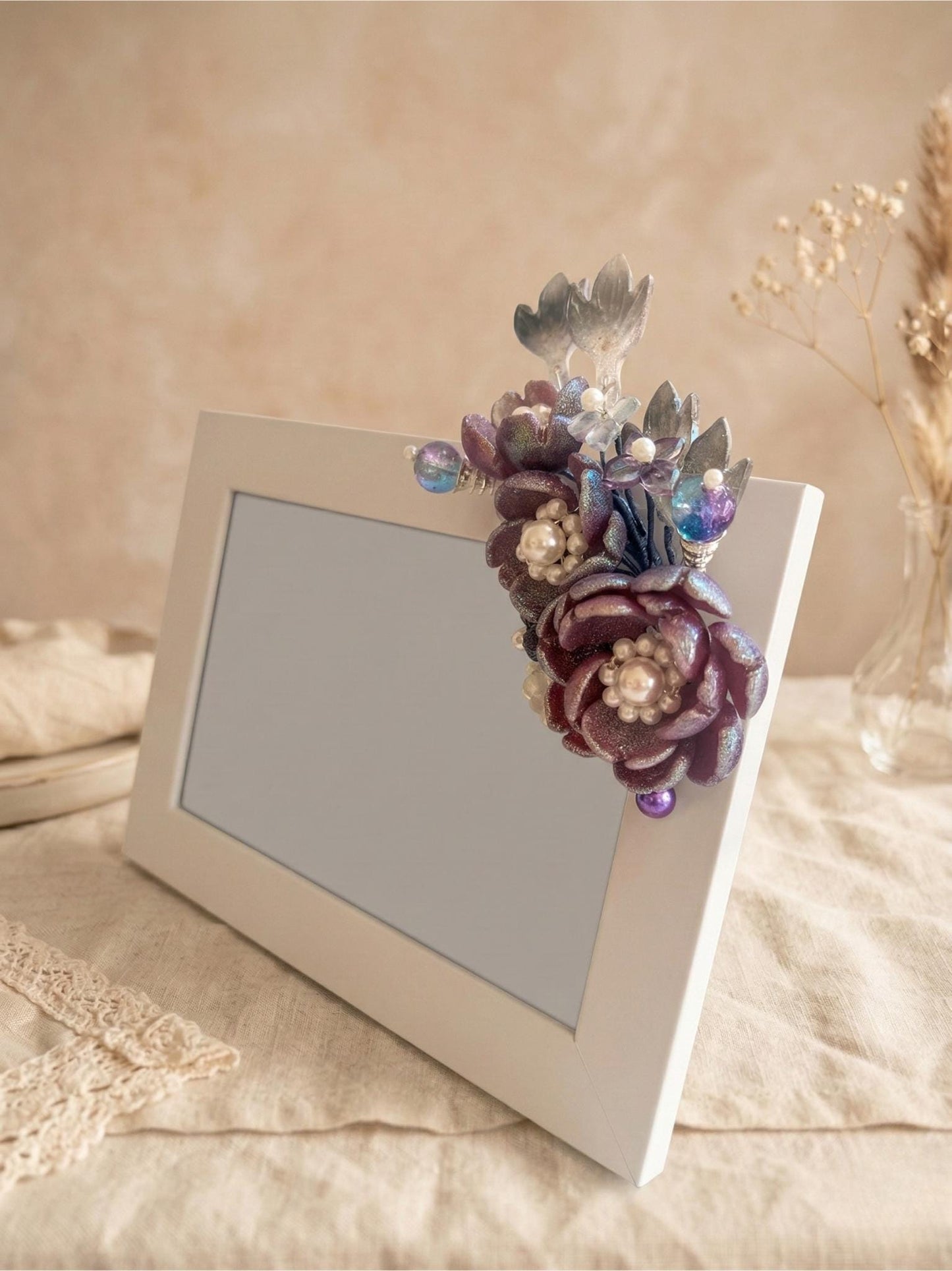 Deep purple and iridescent blue glass flowers with pearls on a white frame