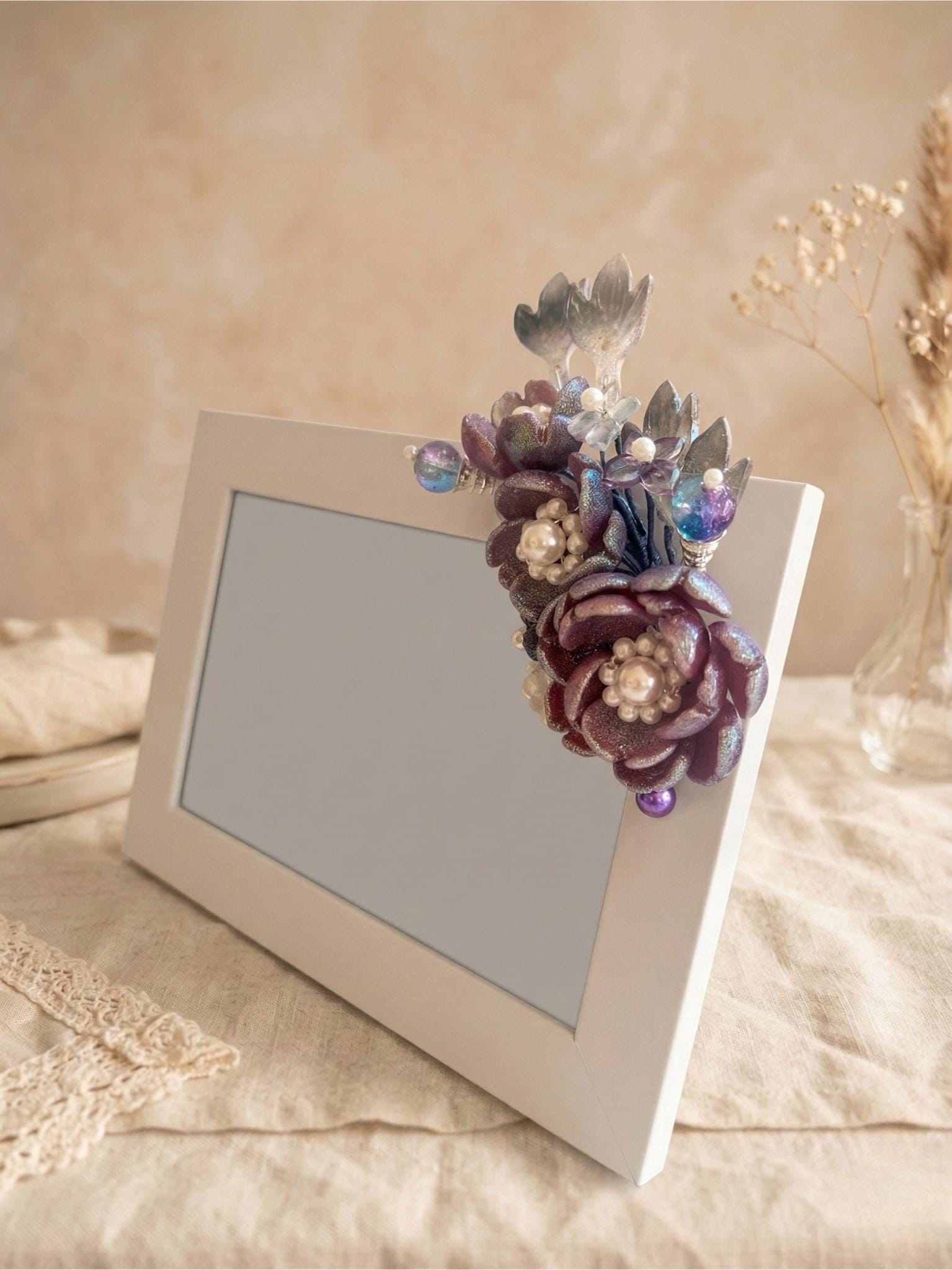 Deep purple and iridescent blue glass flowers with pearls on a white frame