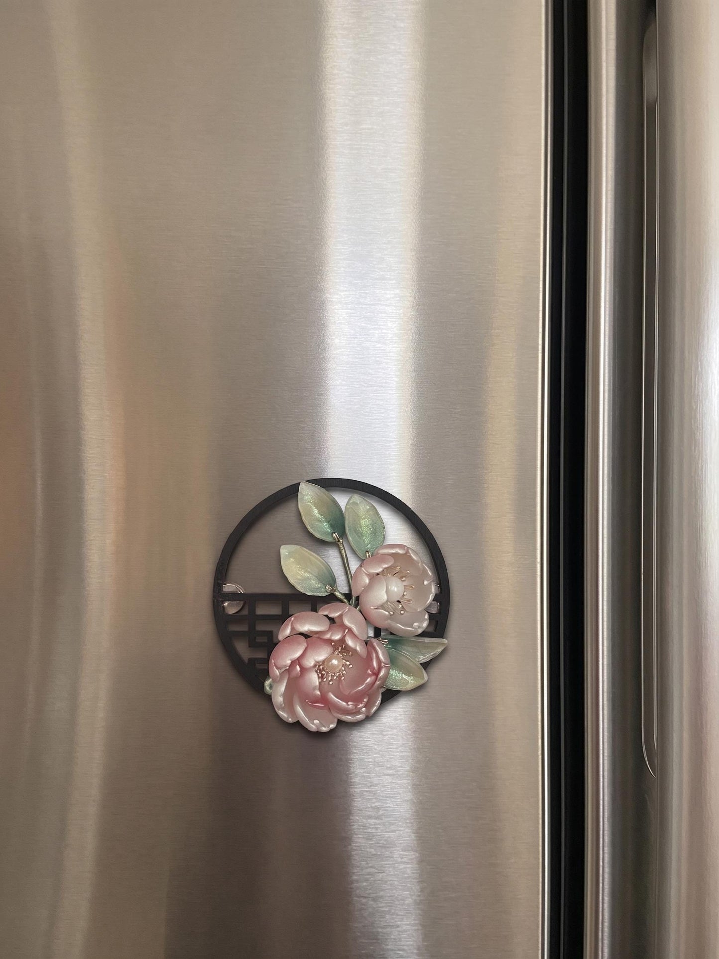 Glass peony flower magnet on a fridge surface