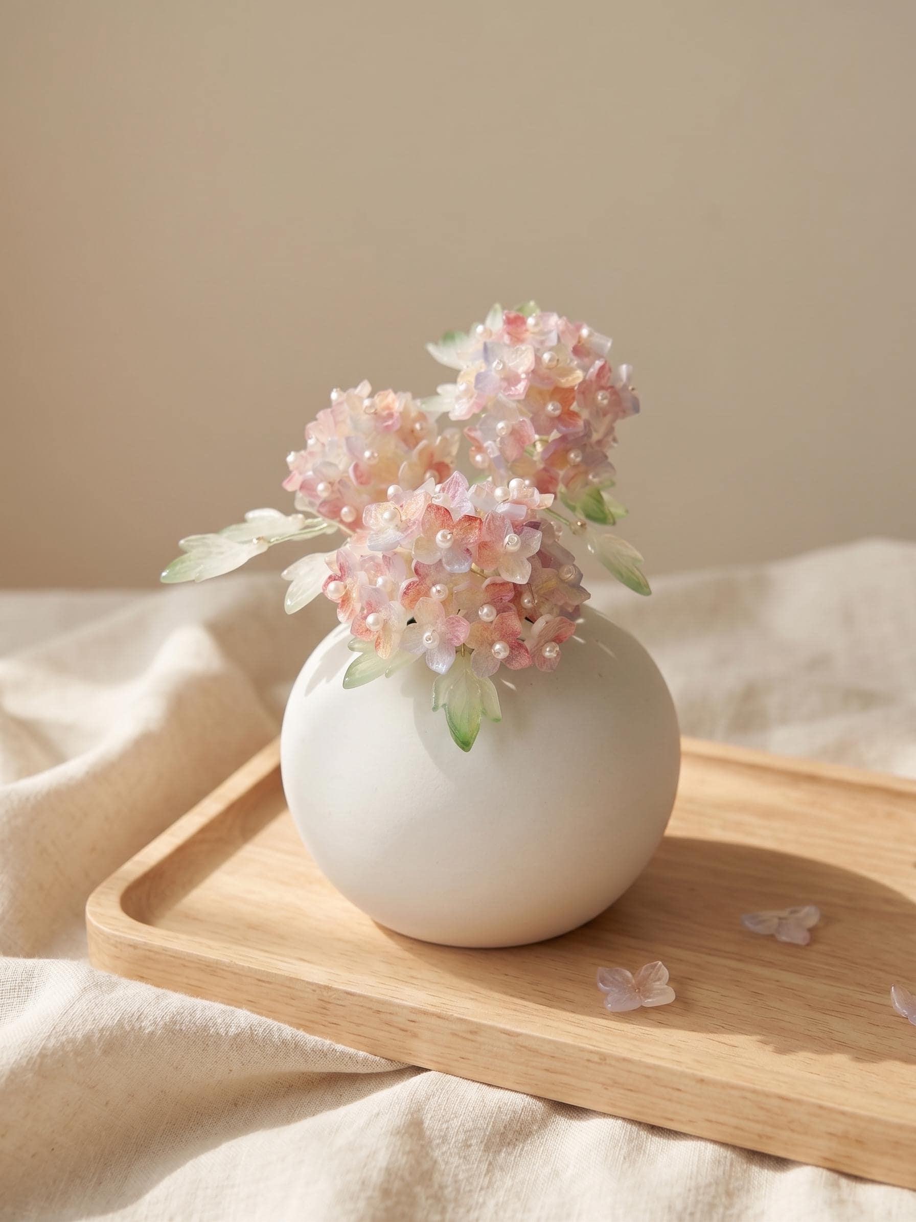 Pink glass hydrangea arrangement in a round white ceramic vase